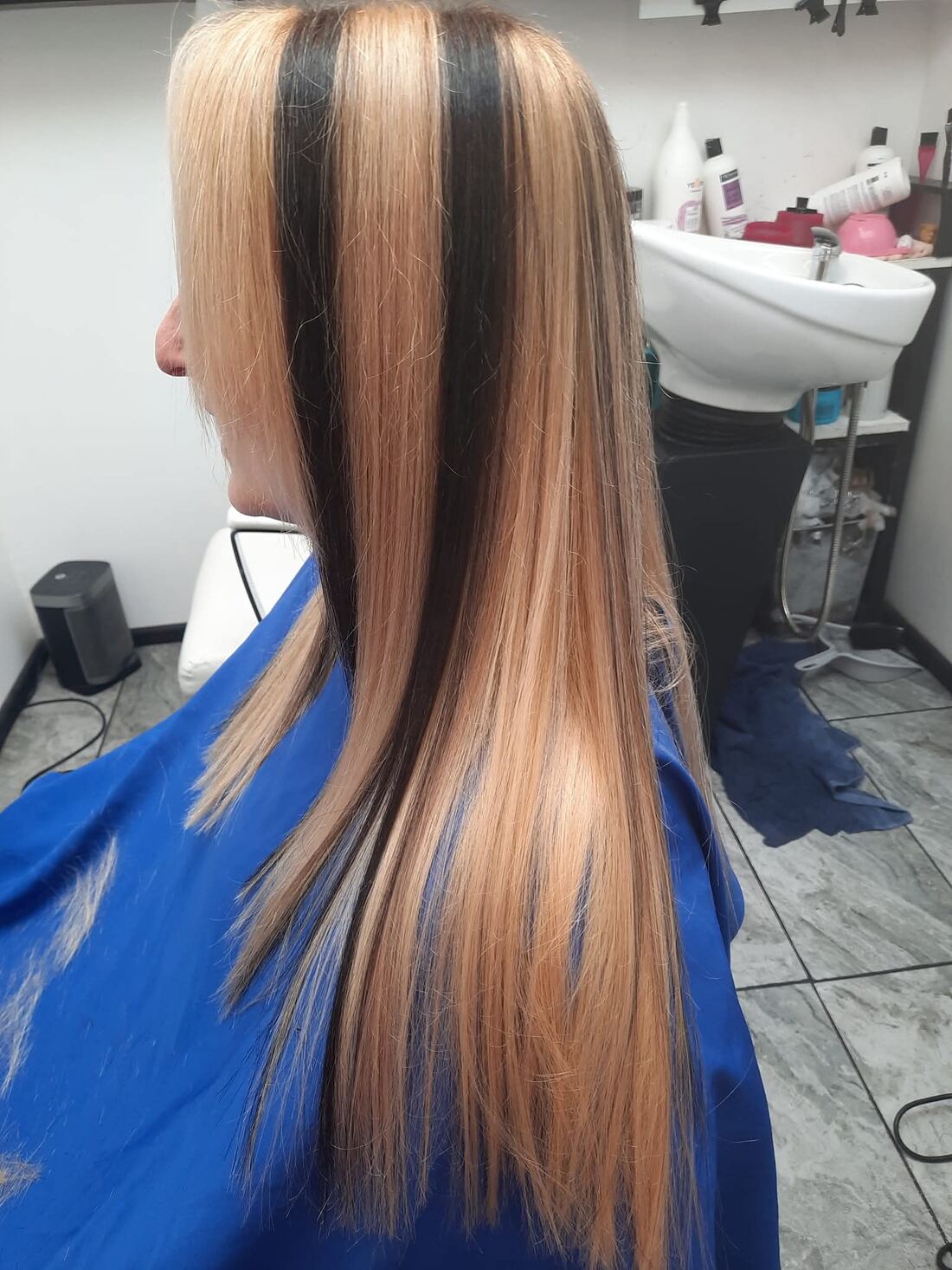 Long blonde hair blow-dried poker straight, with deep contrasting dark panels running from the parting to the ends.